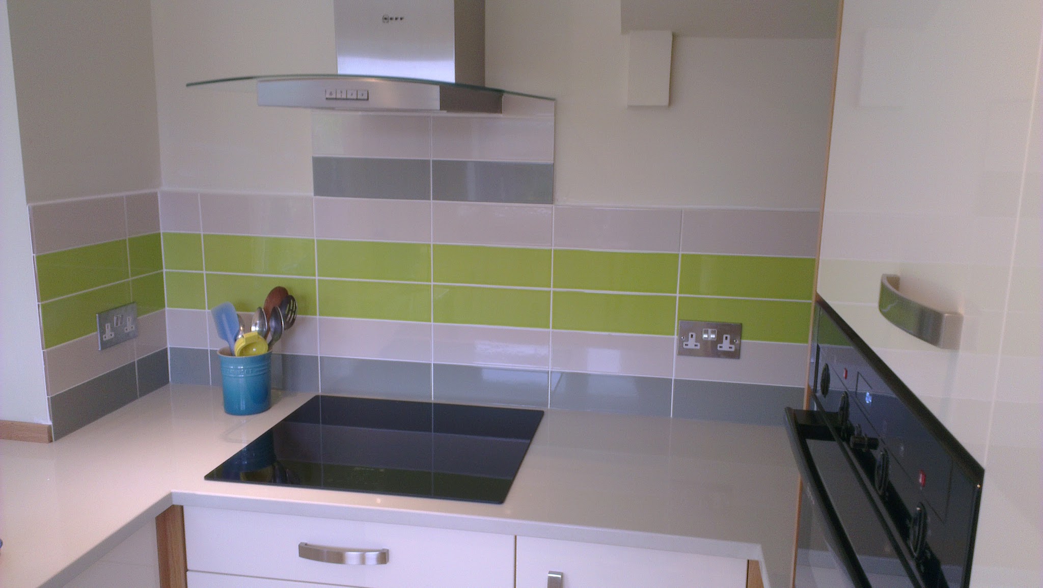 Brushed-steel double sockets above a white worktop and a tiled splashback in a finished kitchen